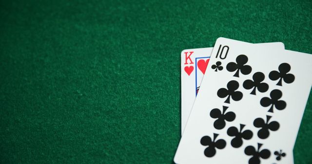 This detailed close-up depicts two playing cards on a poker table in a casino. It can be effectively used in articles or advertisements related to casinos, online gambling platforms, poker tutorials or promotions, and high-stakes gaming events. The capture of the ace and king suggests high-value cards, which could also focus on themes of luck, skill, and excitement in the gambling world.