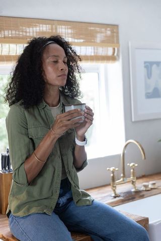 African american woman savoring morning coffee on kitchen counter, mindful relaxation