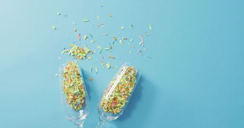 Champagne glasses with confetti on blue background