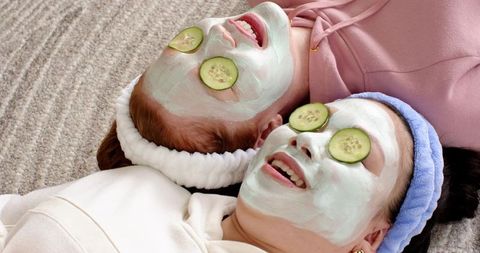 Friends enjoying home spa night with face masks and cucumber eye slices, cozy self-care