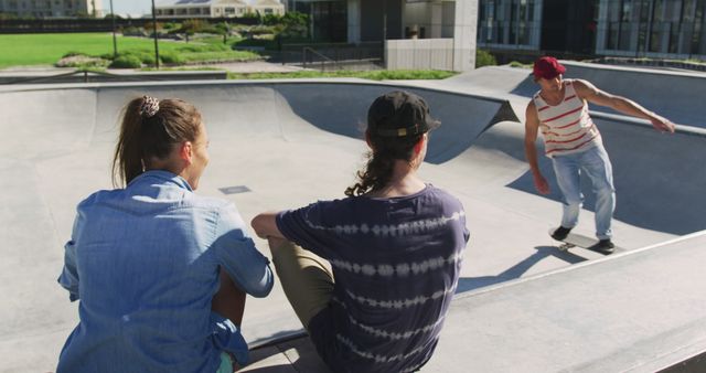 Teenage skateboarder performing a trick on skateboard ramp, with two friends sitting and watching. Ideal for usage in content related to youth activities, sports, friendship, urban lifestyle, and motivations for active living.