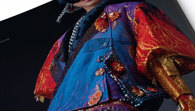 Dramatic couture: ornate embroidered blue jacket on male model with heavy chain