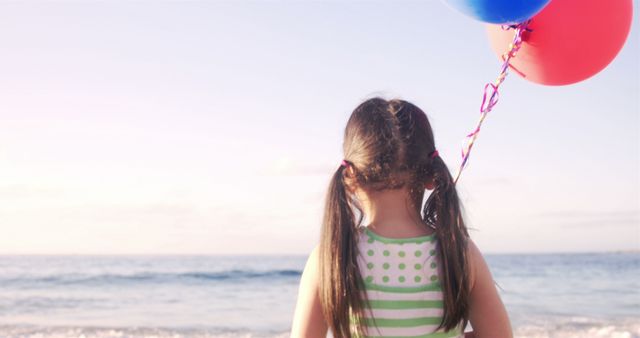 Young girl holding balloons at the beach - Download Free Stock Images Pikwizard.com