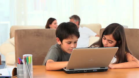 Children Engaging with Laptop While Parents Relaxing in Background
