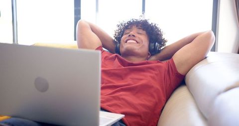 Young Man Relaxing with Headphones and Laptop on Sofa