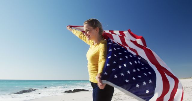 Woman holding American flag on sunny beach with bright blue sky, representing American pride and patriotism. Suitable for Fourth of July celebrations, patriotic events, and USA travel marketing. Perfect for illustrating themes of freedom, happiness, and outdoor joy.