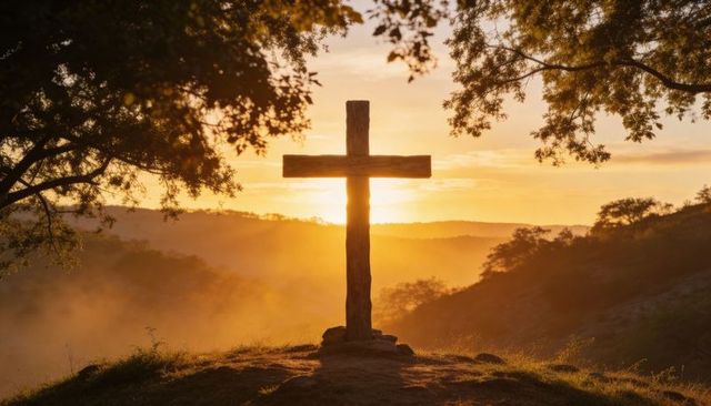Sunrise wooden cross on hilltop silhouette with misty valley and golden halo