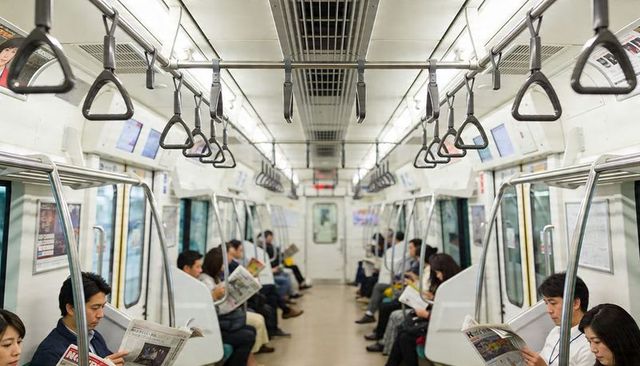 Commuters Reading Newspapers on Urban Subway Carriage During Morning Rush Hour, Holding Straps