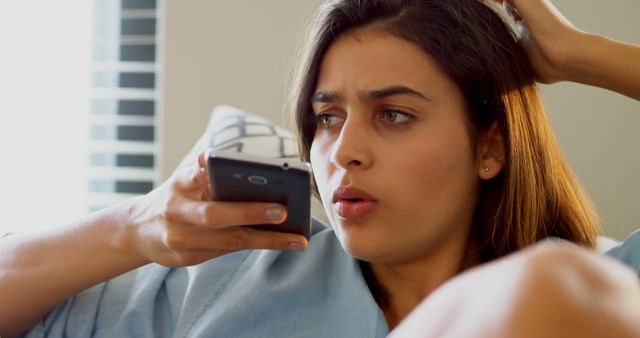 Confused Woman Holding TV Remote in Living Room - Download Free Stock Images Pikwizard.com