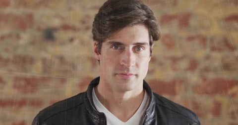 Stylish man in leather jacket front brick wall