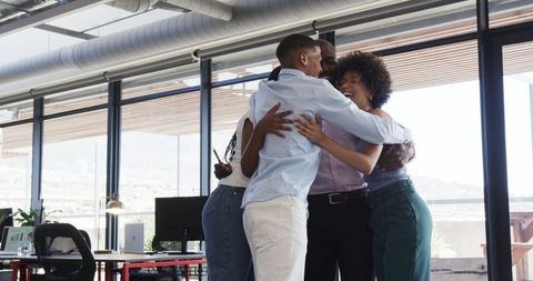 Diverse Team Hugging and Celebrating Success in Modern Office