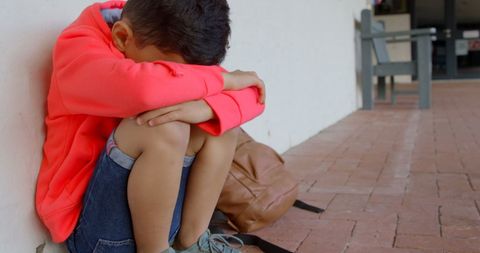 Sad Young Boy Sitting Alone at School Corridor with Head Down - Download Free Stock Images Pikwizard.com