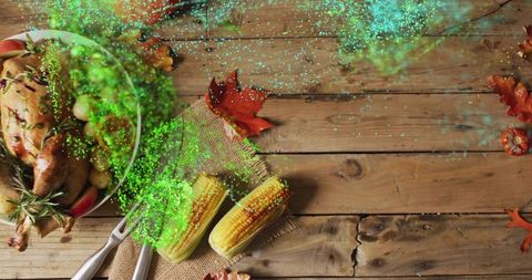 Roasted turkey centerpiece featuring corn on cob on rustic wood table and autumn leaves
