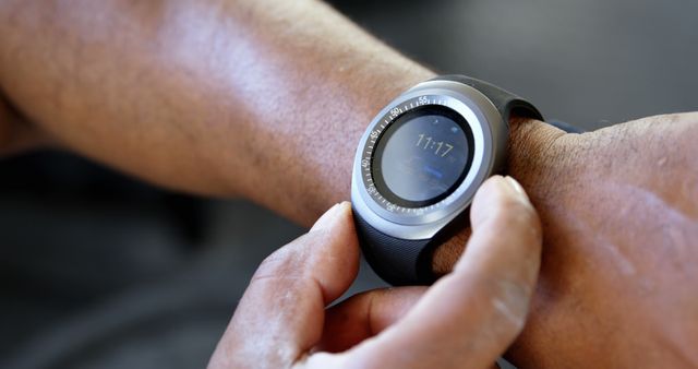 Person interacting with smartwatch, showing close-up of the device on wrist with finger. Ideal for illustrating technology usage, wearable gadgets, lifestyle, and precision checking time. Suitable for articles on modern devices, fitness tracking, and personal technology.