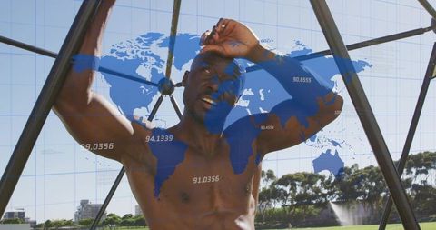 Muscular mature man shading eyes while holding metal frame with blue world map overlay