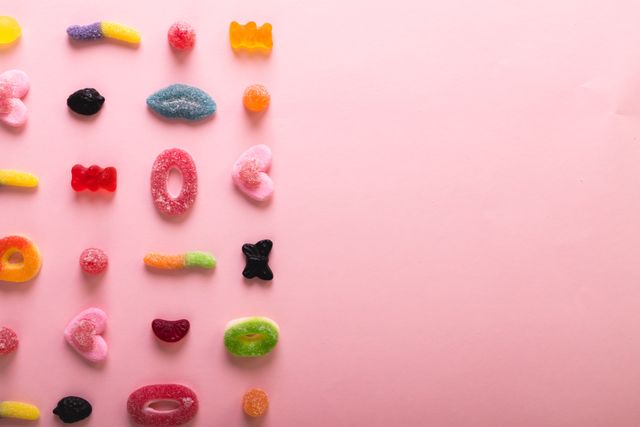 Directly above view of fresh various sugar candies by copy space on pink background. unaltered, unhealthy eating and sweet food concept.