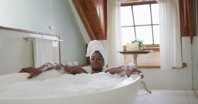 African american attractive woman relaxing in foam bath in bathroom. beauty, pampering, home spa and wellbeing concept.