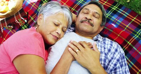 Senior Latino Couple Relaxing on Picnic Blanket Together