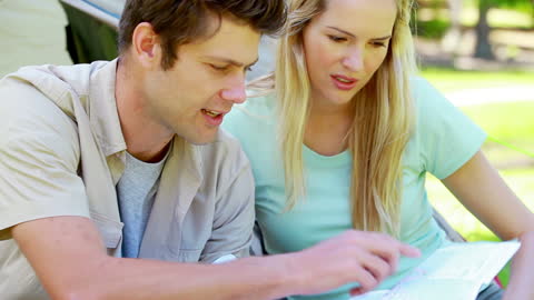Couple Exploring Directions with Map at Campsite