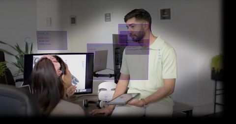 Man reviewing 3d render on monitor with tablet and ar annotations in modern workspace
