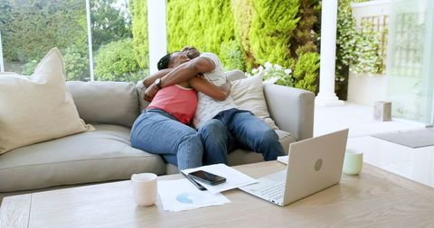 Happy Couple Embracing on Sofa While Working from Home