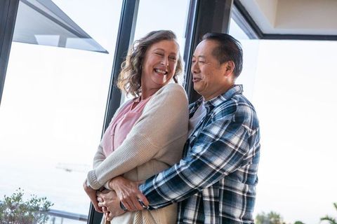 Diverse Senior Couple Embracing on Seaside Balcony
