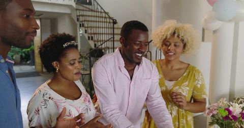 Black Friends Celebrating Birthday Cutting Cake at Home with Balloons and Flowers