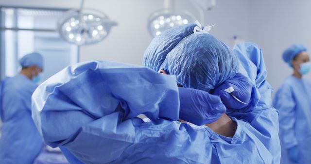 Surgeons preparing for surgery in a sterile hospital environment. They are wearing blue scrubs and surgical caps, focusing on ensuring a sterile setting before the procedure. Useful for websites and publications related to healthcare, medical procedures, hospital operations, and surgical teams.