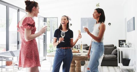 Three Female Friends Celebrating with Drinks Indoors
