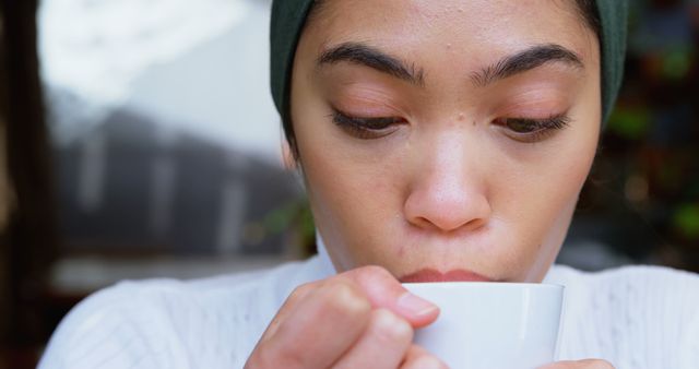 Young Woman Sipping Warm Beverage from Mug in Cozy Setting - Download Free Stock Images Pikwizard.com