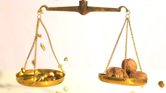 Gold nuggets are stacked in one side, while nutmeg nuts rest on the other, symbolizing a comparison of wealth and organic ingredients. Possible uses include illustrating thematic concepts of balance, wealth, valuation, and alternative services in presentations, articles, or educational content.