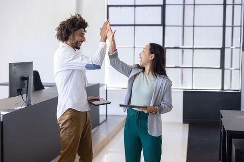 Diversified Team High-Fiving in Modern Open-Plan Office Environment