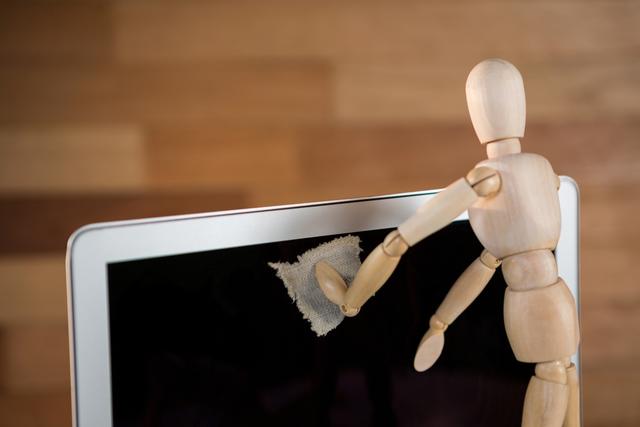 Conceptual image of figurine cleaning laptop