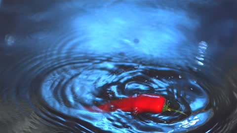 Red Chili Splashing Into Water Creating Ripple Effect