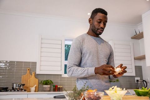 African American Man Peeling Garlic in Modern Kitchen