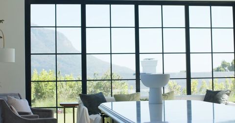 Minimalist Modern Interior with Black-Framed Window Wall, Garden View and Glossy White Table