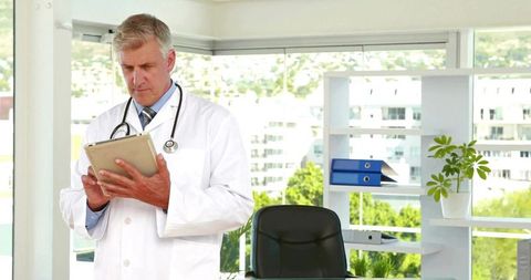 Senior doctor using tablet for medical records in urban office
