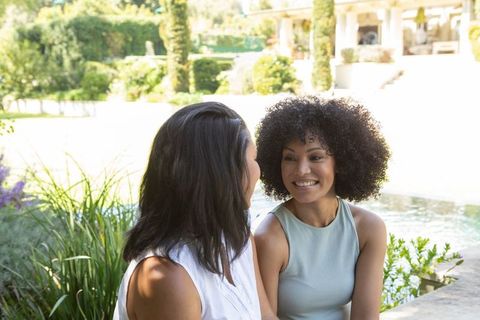 Mother and Daughter Chatting By Garden Water Feature