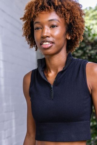 Confident african american woman wearing black ribbed crop top outdoor portrait curly auburn hair