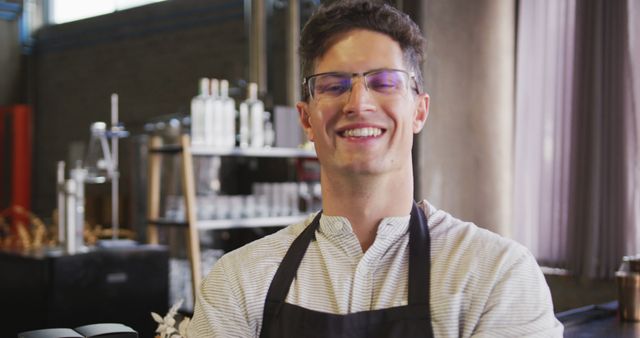 Portrait of happy caucasian man wearing apron working at a cafe bar, smiling to camera. work at an independent bar, open again for business after pandemic lockdown.