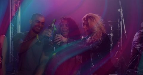 Friends Toasting with Bottles at Nightclub Celebration
