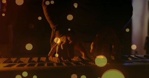 Musician playing keyboard in ambient lighting with bokeh effect