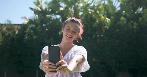 Hispanic Woman Enjoying Sunny Day in Garden Taking Selfie