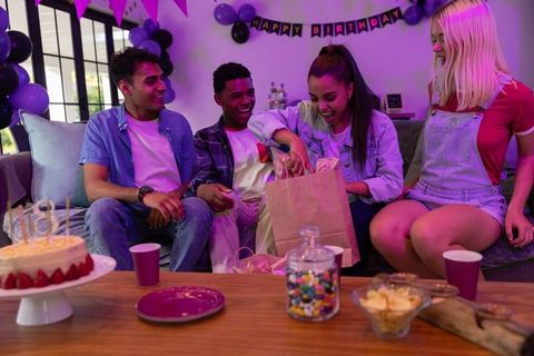 Teen Opening Gift Bag at Birthday Party Surrounded by Friends