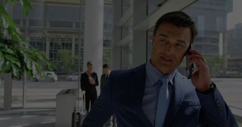 Professional Businessman Engaging in Phone Call in Modern Lobby Setting