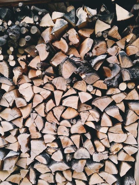 Neatly arranged stack of chopped firewood logs, perfect for use as a rustic background or in publications regarding fire safety, natural resources, and wood preparation. This can be utilized in home improvement blogs, camping guides, and eco-friendly content