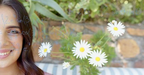 Young woman smiling on patio with handwritten trigonometry on glass and daisies