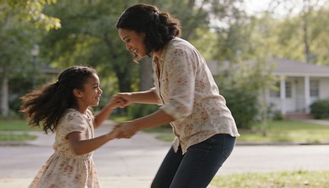 Mother spinning daughter on suburban sidewalk laughing sunny afternoon family bonding