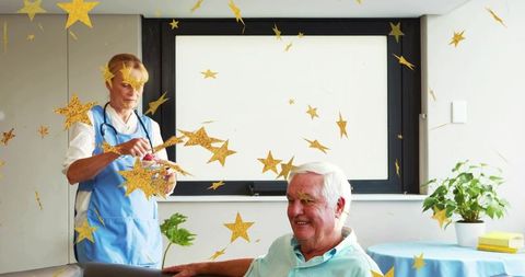 Smiling senior man sitting with caregiver holding gold stars celebrating companionship