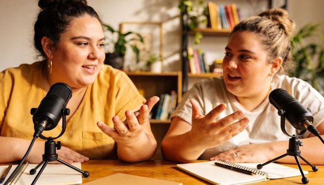 Two women cohosts recording conversational podcast in cozy home studio
